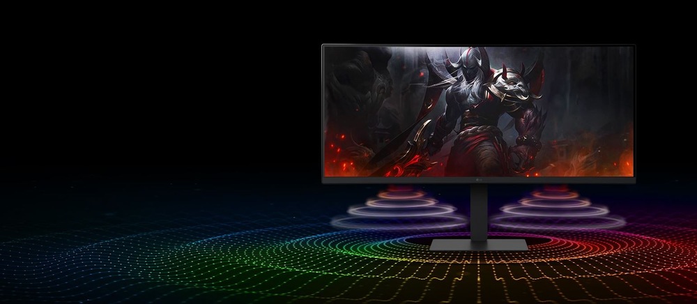 Širokouhlý počítačový monitor zobrazuje fantasy bojovníka v brnení na tmavom pozadí. Z obrazovky vychádzajú žiarivé, farebné zvukové vlny, ktoré vytvárajú dynamickú a pohlcujúcu atmosféru.