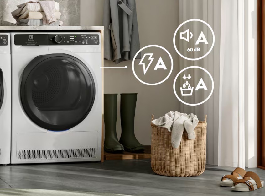Sušička bielizne Electrolux PerfectCare 900 EW9D595CC biela Sušička Electrolux, vpravo symboly pre energetickú triedu A. Vpravo pri sušičke sú postavené gumáky a kôš na bielizeň.
