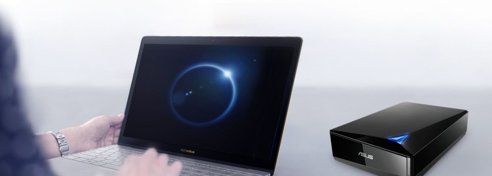 Externá Blu-ray napaľovačka Asus TurboDrive BW-16D1X-U BDXL Blu-ray USB-A čierna Osoba používa notebook a na obrazovke sa zobrazuje svietiaci modrý kruh. Vedľa neho na svetlom povrchu leží elegantná čierna externá Blu-ray napaľovačka Asus.