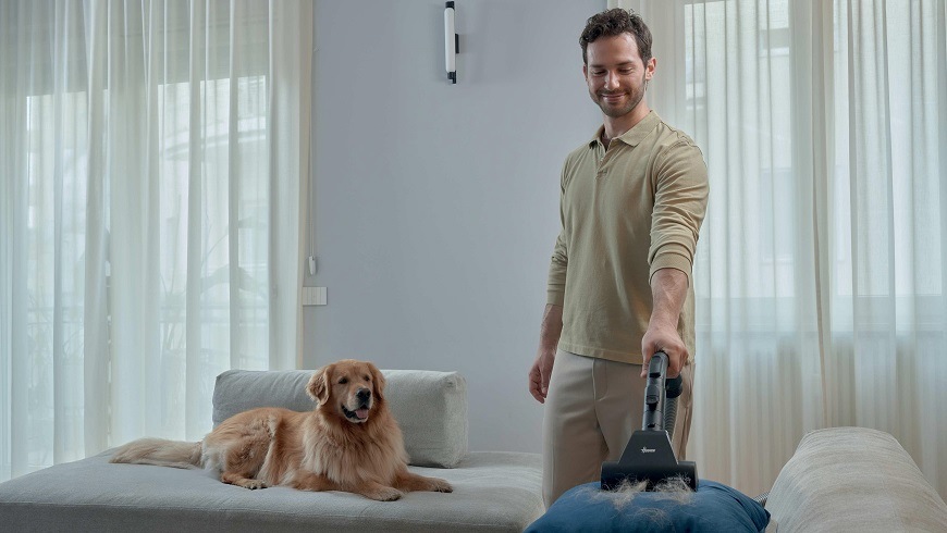Podlahový vysávač Hoover HP410P 011 čierny/béžový HP410P 011 muž vysáva psie chlpy z vankúšika, na gauči leží retriever