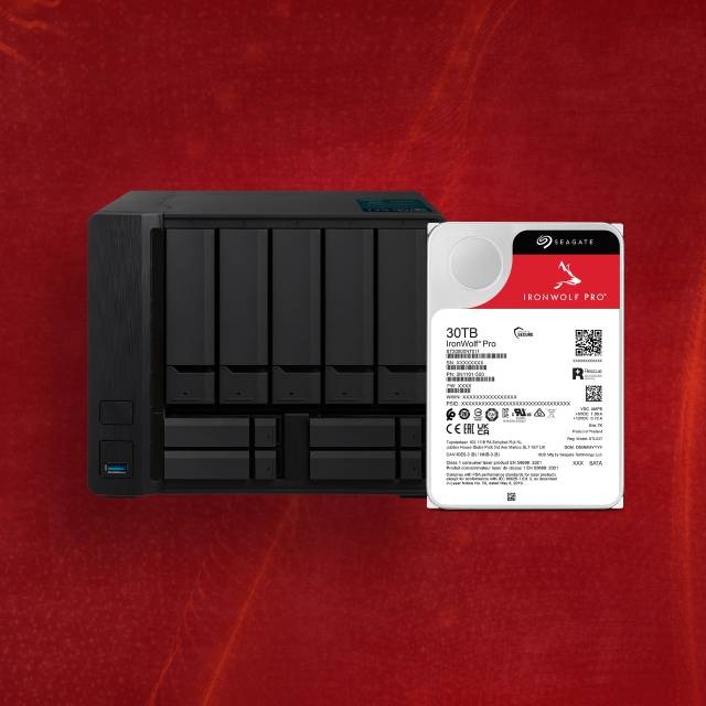 Čierne úložné zariadenie RAID s niekoľkými slotmi je vedľa pevného disku Seagate IronWolf Pro 30TB na žiarivo červenom textúrovanom pozadí.