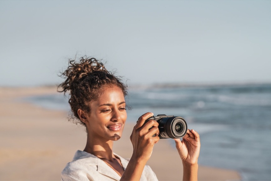 Digitálny fotoaparát Sony Alpha 6700 + 16-50 mm f/3.5-5.6 II čierny Žena natáča video na pláži s kompaktným fotoaparátom Sony Alpha 6700 so 4K rozlíšením videa