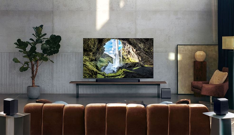Soundbar Samsung HW-Q990H čierny soundbar samsung pod televíziu samsung v modernej obývacej izbe. Vedľa TV je rastlina a naproti gauč. V telvízii je premietnutá príroda, skaly a padajúca voda.
