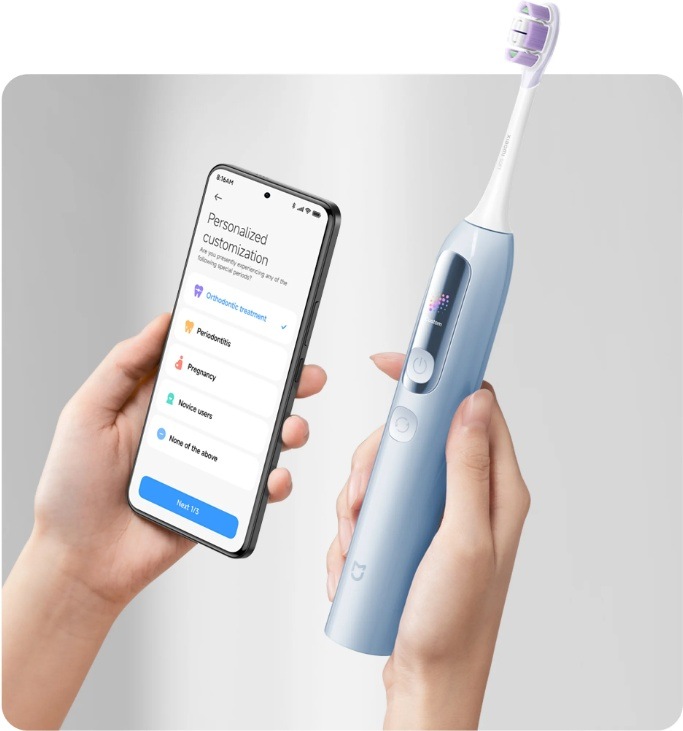 Zubná kefka Xiaomi Mijia MES613 Smart Servo-oscillation Pro EU Blue modrý Ruky držia modrú elektrickú zubnú kefku Xiaomi MES613 a chytrý telefón s otvorenou obrazovkou pre prispôsobenie nastavenia čistenia