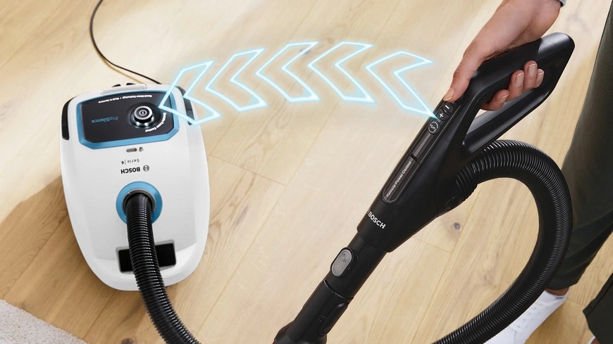 Vysávač Bosch BGB6SIL0L a modré šípky znázorňujúci možnosť diaľkového ovládania sacieho výkonu priamo na rukoväti