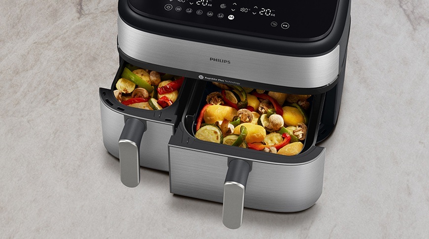 Fritéza teplovzdušná Philips Airfryer Dual Basket 5000 series 9 l, NA555/00 strieborná Teplovzdušná fritéza Philips NA555/00 má povysunuté oba košíky. Vnútri nich sa práve pripravila lahodná zelenina.