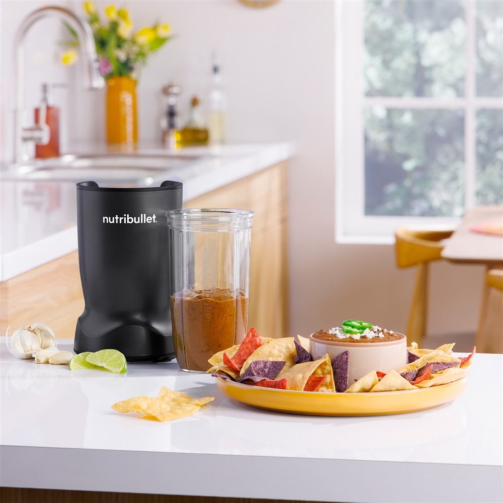 Stolný mixér Nutribullet TURBO 1000 NBT1006MB čierny Mixér NutriBullet použitý na prípravu omáčky, vedľa taniera s tortilla chips a dipom.