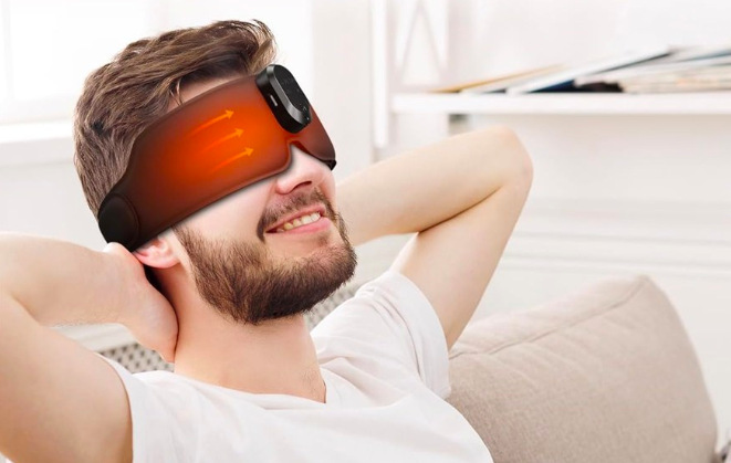 Masážny prístroj na očné okolie RENPHO Eyesnooze GS003 čierny Muž odpočíva s vyhrievanou maskou RENPHO GS003 na očiach a uvoľňuje sa na gauči