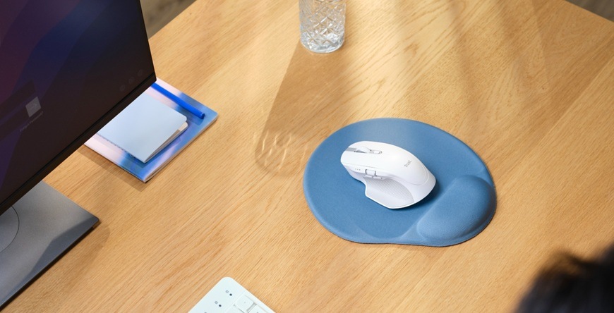 Podložka pod myš Trust BIGFOOT v modrom prevedení je položená na pracovnom stole a na nej je biela myš.
