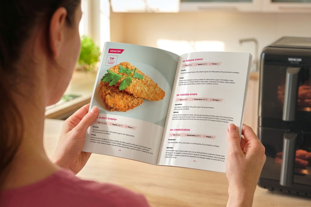 Žena drží v ruke kuchárku, ktorá je v balení s teplovzdušnou fritézou Sencor SNR 1260BK