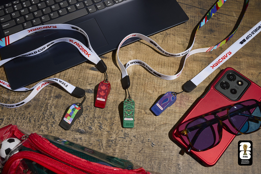 USB flashdisk SANDISK USB-C Flash Drive FIFA World Cup 2026 64GB čierny Kolekcia USB flashdiskov SanDisk FIFA World Cup 2026 položená vedľa notebooku a telefónu