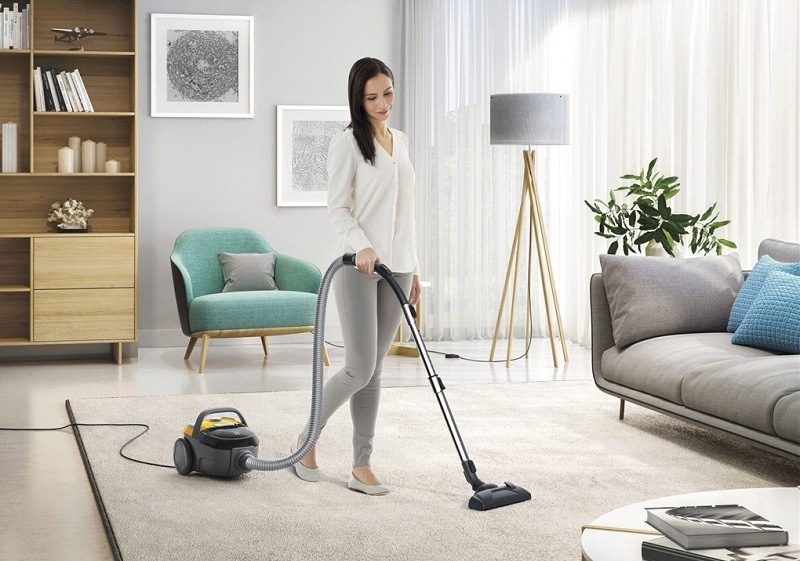 Podlahový vysávač Electrolux CompactGo Cyclonic ECGC21-2Y žltý Žena v obývačke vysáva koberec s pomocou vysávača Electrolux.