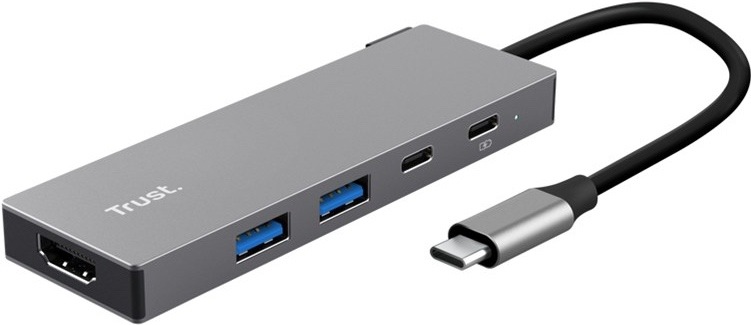 USB Hub Trust DALYX 5v1 strieborný Na obrázku je strieborný USB-C hub Trust DALYX 5v1 zachytený šikmo spredu. Má úzke kovové telo s čistým hranatým dizajnom a z jedného konca z neho vedie krátky čierny kábel zakončený USB-C konektorom. Na ľavom čele je HDMI konektor, na boku dva modro značené USB porty a dva menšie USB-C porty, vedľa ktorých je malá kontrolka.