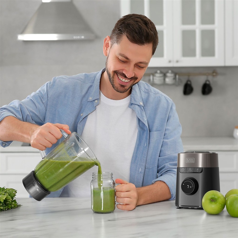 Stolný mixér Black+Decker BXJB1201E čierny Muž prelieva hotové zelené smoothie z mixéra Black+Decker do skleneného pohára.