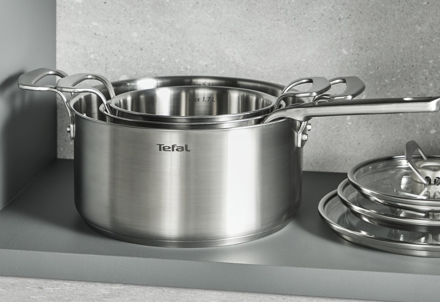 Sada riadu Tefal Extreme E529SA25, 10 ks nerez Súprava nerezového náčinia je položená na šedej kuchynskej linke.