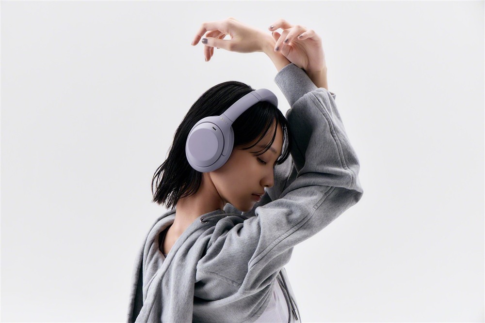 Slúchadlá Sony WH-1000XM4C fialová Žena so slúchadlami Sony WH-1000XM4C pri počúvaní hudby a tanca