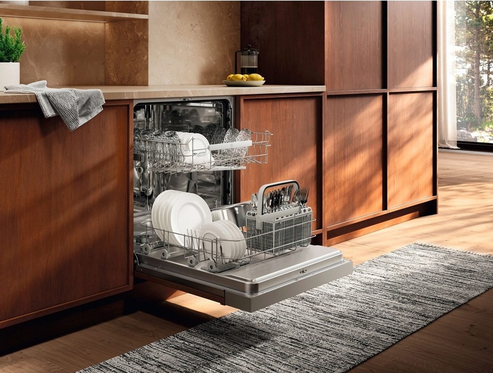 Umývačka riadu Electrolux série 500 E52ID100SX Otvorená umývačka Electrolux E52ID100SX séria 500 plná riadu v kuchyni s dreveným dekorom.