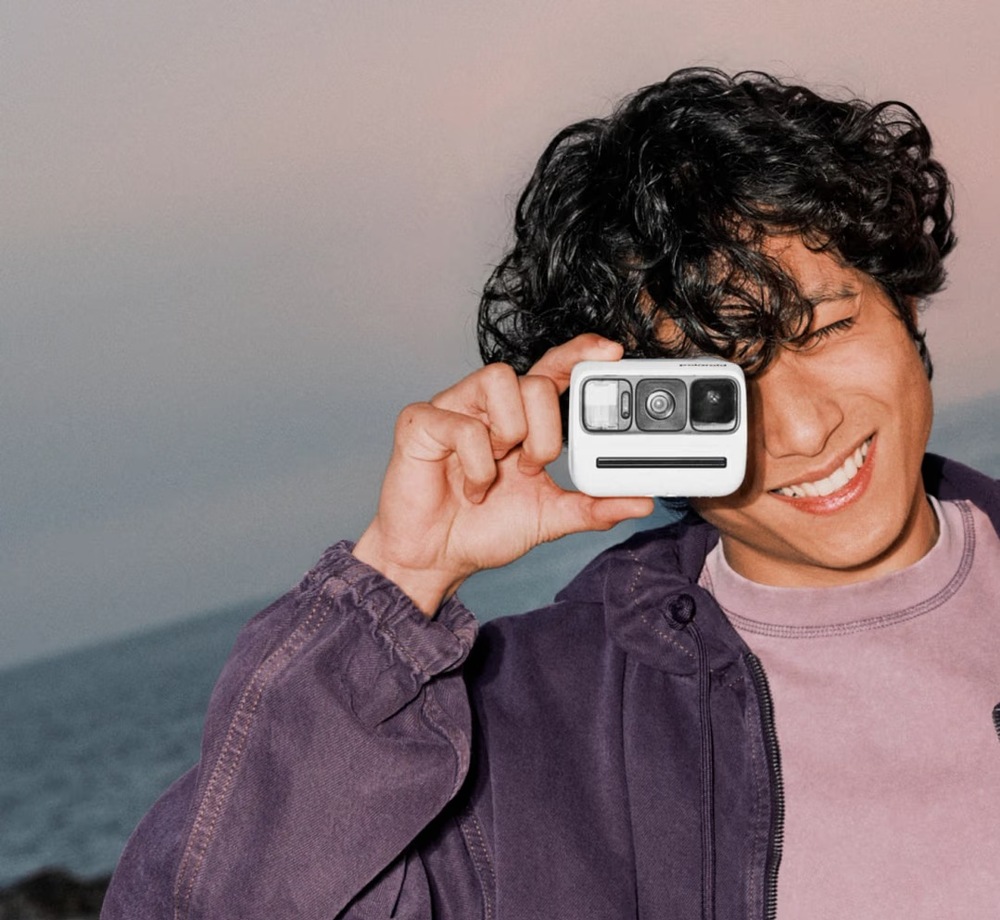 Instantný fotoaparát Polaroid Go Gen 3 tyrkysový Smejúci sa muž fotografuje pomocou miniatúrneho fotoaparátu Polaroid Go Gen 3″ width=