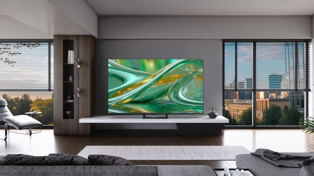 Televízor Hisense 50E8S televízia Hisense 50E8S v modernej izbe. Na TV je zelené pozadie, v izbe je kreslo, gauč, stolík a veľké okná s výhľadom