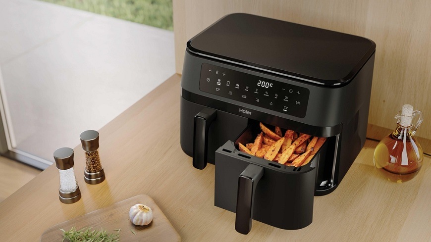 Teplovzdušná fritéza Haier HAF3AD 011 na kuchynskej linke, vedľa nej sa nachádza ingrediencie, jeden kôš je otvorený a sú v ňom hranolky