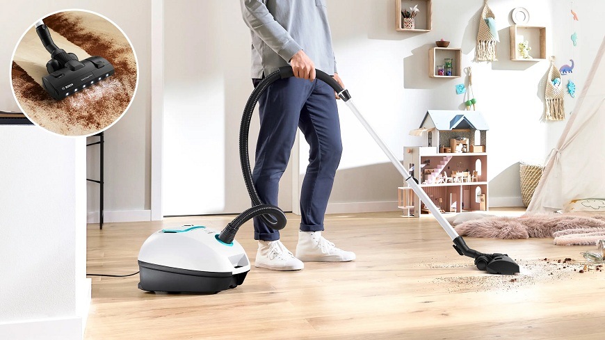 Muž vysávajúci s vysávačom Bosch BGL41HYG0L svetlý svetlú podlahu v obývacej izbe