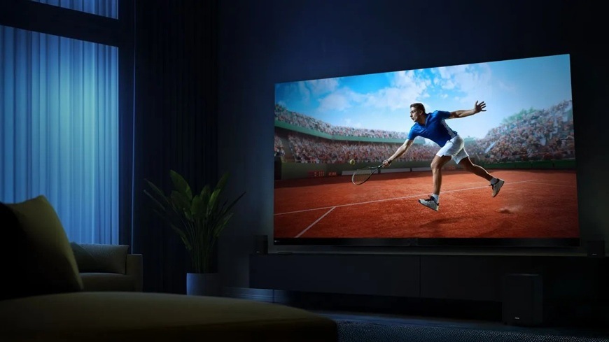 Televízor Hisense 136MX Hisense TV 136MX v tmavej obývačke zobrazuje dynamickú scénu tenisového zápasu s hráčom v pohybe. Plynulé zobrazenie, ostré detaily a vysoký kontrast zdôrazňujú ideálne podmienky.