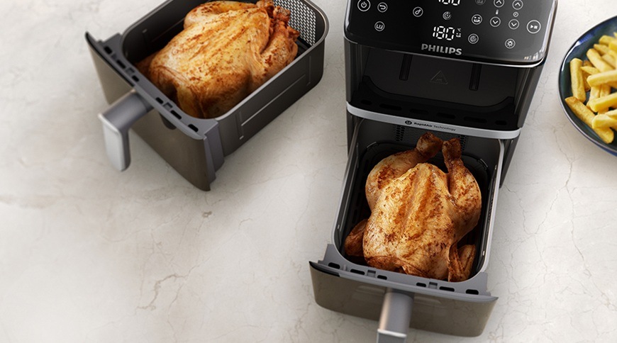 Fritéza teplovzdušná Philips Airfryer Dual Basket 4000 series 10 l, NA461/00 čierna Teplovzdušná fritéza Philips NA461/00 s dvoma vysunutými košmi, v ktorých sú pripravované celé kurčatá, vedľa na linke je tanier s hranolkami.