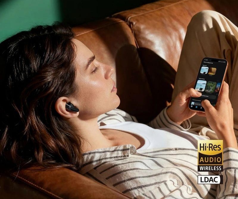 Žena so slúchadlami Soundcore Liberty Buds drží v ruke smartfón s hudobnou aplikáciou
