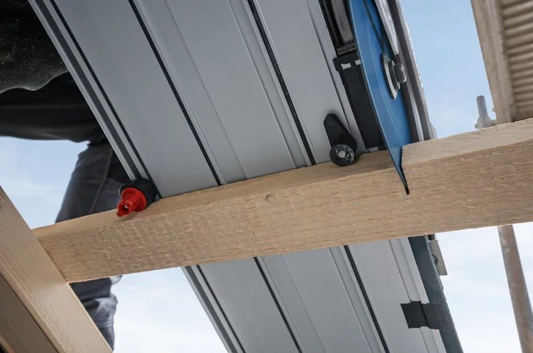 Detailný pohľad zospodu na okružnú pílu Bosch Professional GKS 18V-57-2 GX s vodiacou lištou pri reze.
