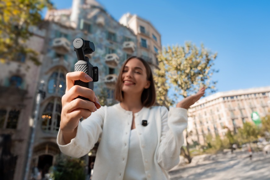 Outdoorová kamera DJI Osmo Pocket 4 Creator Combo čierna Žena pred budovou počas vlogovania.