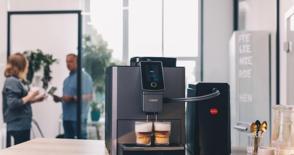 Automatický kávovar Nivona NICR 1040 Automatický kávovar Nivona pri príprave kávy v modernej kuchyni s mliečnymi nápojmi v pohároch