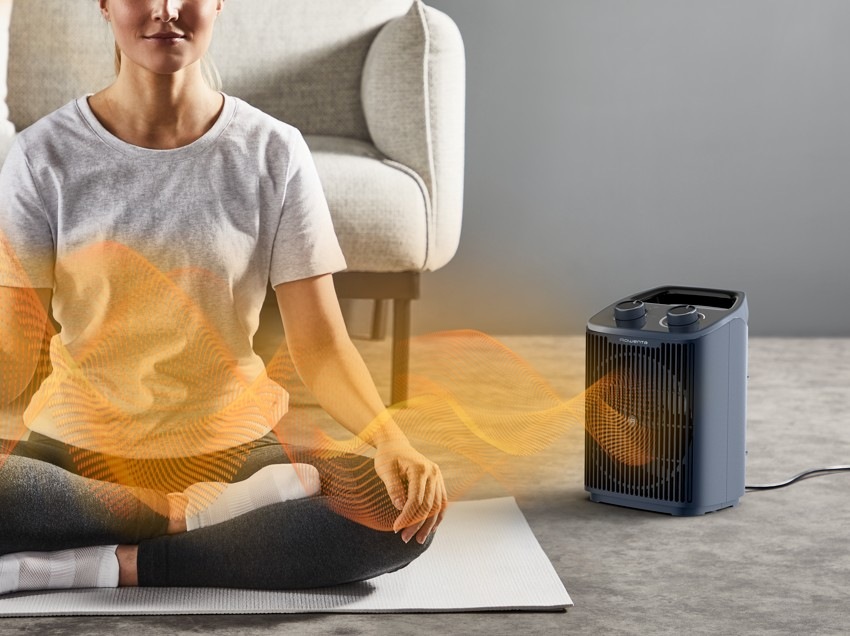 Teplovzdušný ventilátor Rowenta SO2351F0 Intense Comfort sivý Žena medituje na zemi a vedľa nej je teplovzdušný ventilátor Rowenta SO2351F0 Intense Comfort