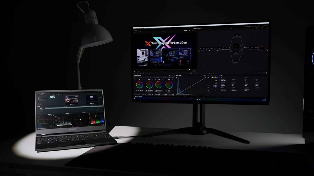 Herný monitor GIGABYTE MO27Q2A čierny Slabo osvetlený pracovný priestor s notebookom a veľkým monitorom s programom pre strih videa. Ilustruje použitie funkcie KVM.