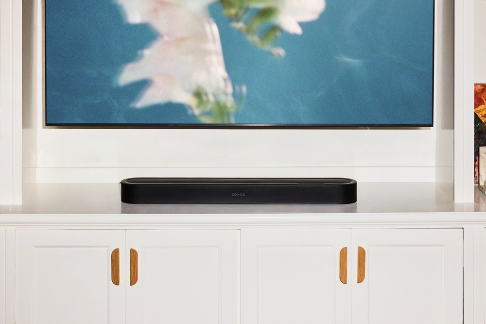 Soundbar SONOS Beam Ultra čierny Čierny soundbar Sonos Beam Ultra umiestnený na bielej TV skrinke pod televíziou v obývacej izbe.