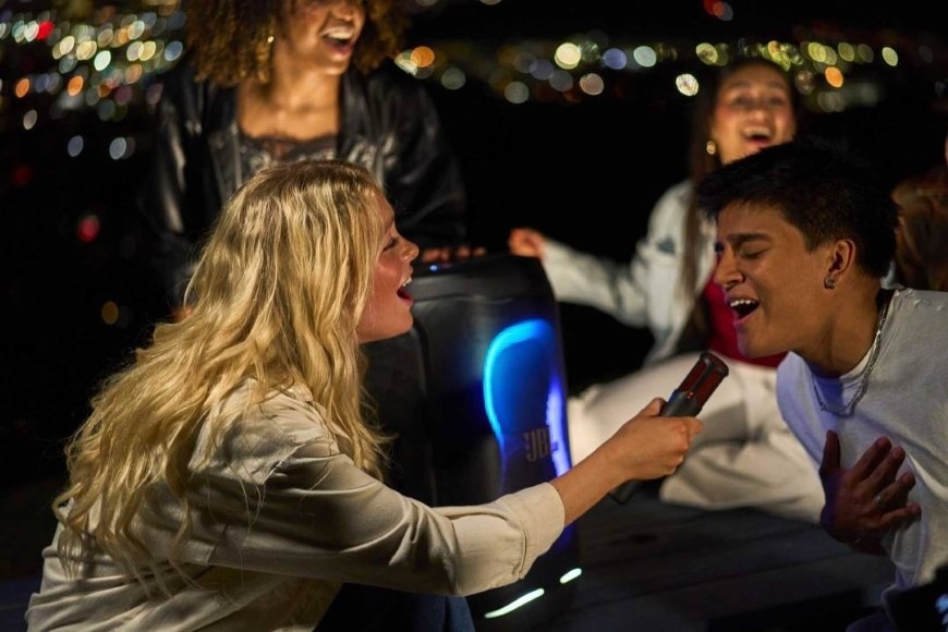 Skupina ľudí sa baví pri karaoke vďaka reproduktoru JBL PartyBox 130 so vstupom pre mikrofón