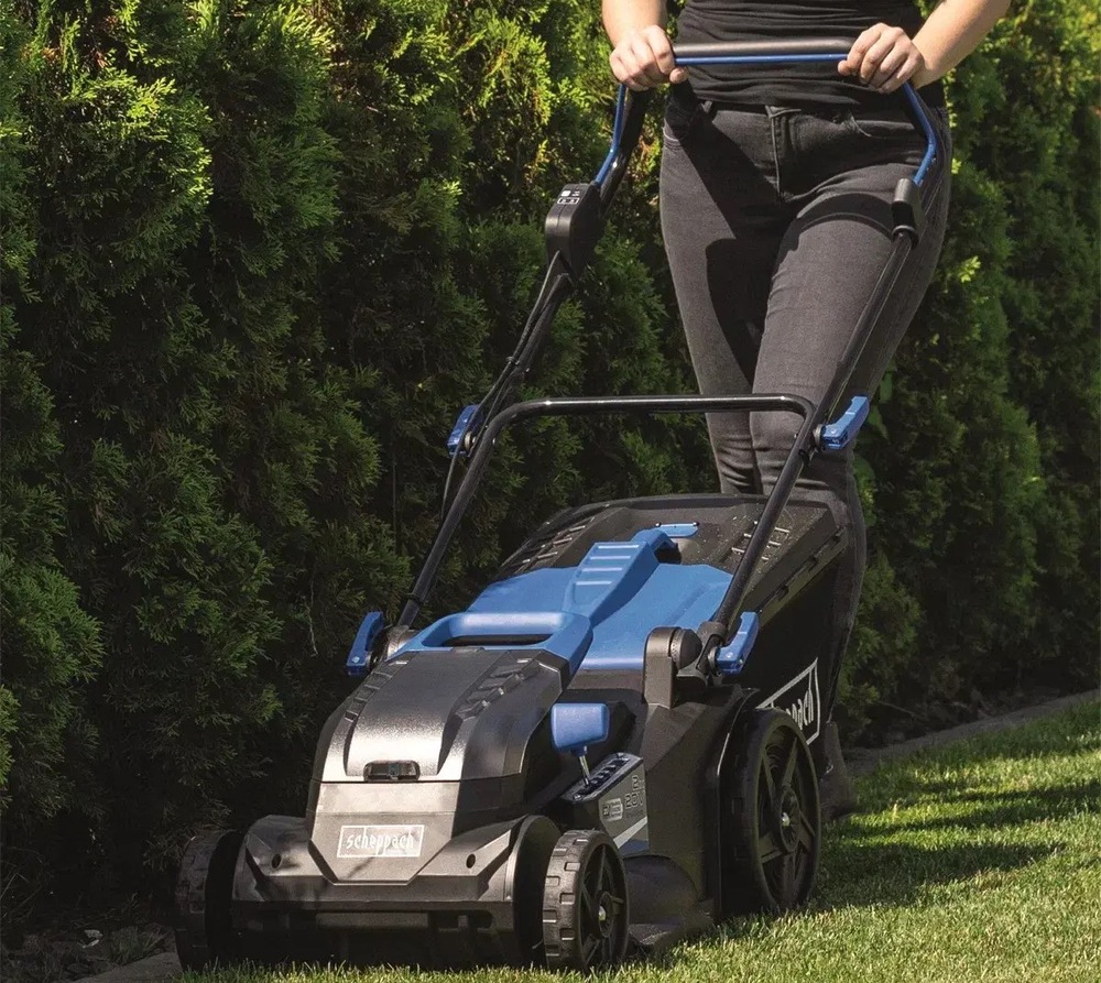 Kosačka Scheppach BC-MP430-X-SET XL2 (s baterií) Pohľad na akumulátorovú kosačku Scheppach BC-MP430-X-SET XL2 pri kosení trávnikov pozdĺž stromov.