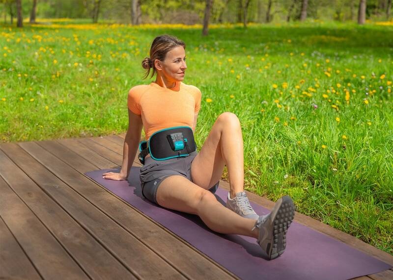 Elektrostimulátor Beurer Corefit II čierny Žena cvičí na podložke v parku s nasadeným stimulátorom Beurer Corefit II