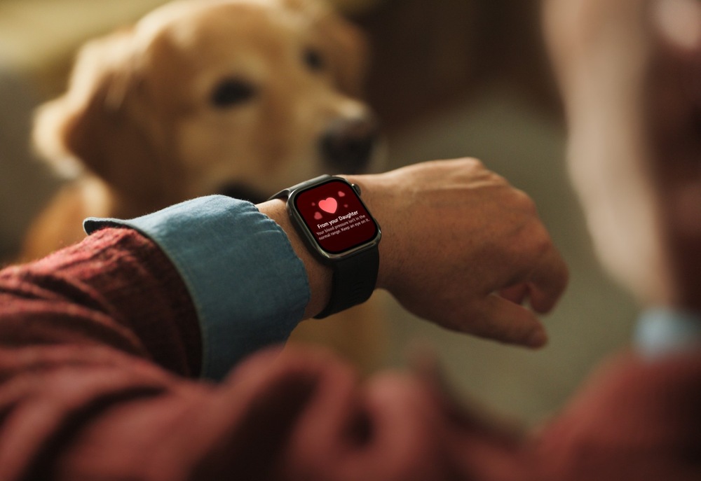 Inteligentné hodinky Huawei Watch D3 čierne Detail inteligentných hodiniek na zápästí staršieho muža; na červenom displeji je upozornenie so symbolom srdca, v pozadí sedí pes