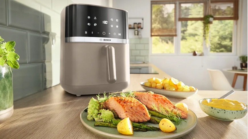 Fritéza teplovzdušná Bosch Serie 4 MAF462C0 béžová Teplovzdušná fritéza Bosch MAF462C0 na kuchynskej linke, pred ňou je na tanieri pripravený losos so zeleninou