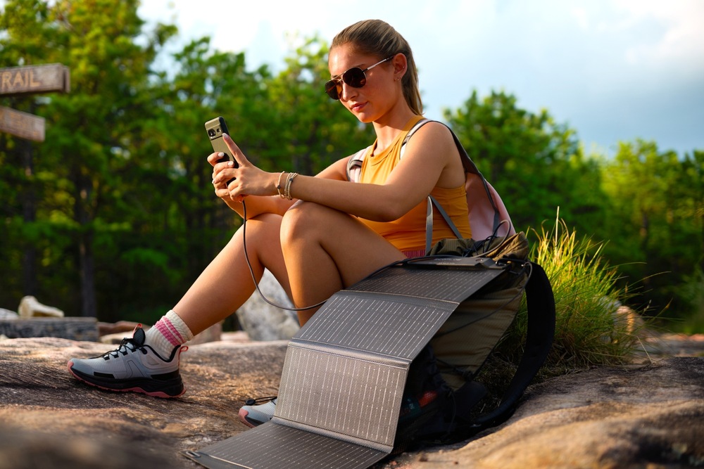 Žena s mobilom v ruke dobíjaným solárnym panelom EcoFlow v prírode