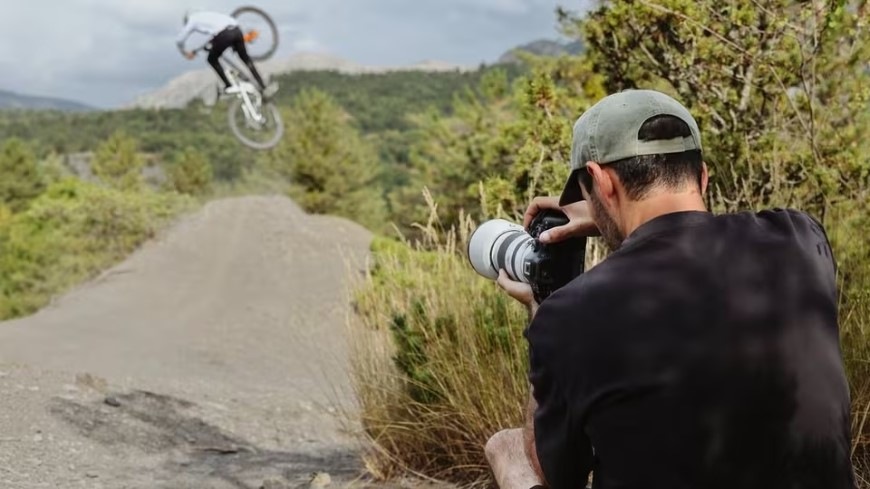 Muž fotografujúci cyklistu s rýchlou bezzrkadlovkou Canon EOS R6 Mark III
