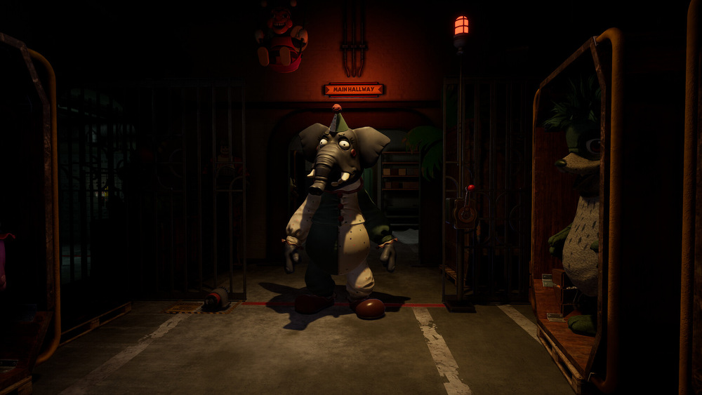 Záber z hry Five Nights at Freddys: Secret of the Mimic. Animatronický slon stojí v temnej, strašidelnej zoo chodbe za mrežami, obklopený klietkami a hračkami pod zlovestným červeným osvetlením.