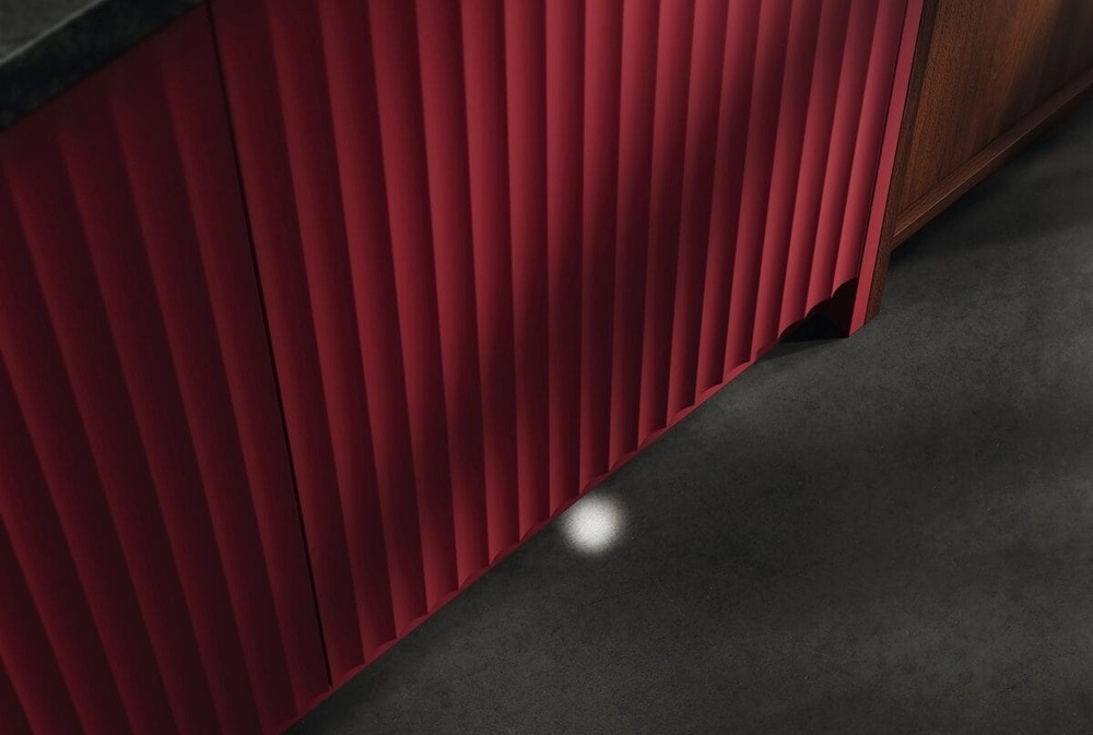 Zatvorená umývačka AEG s červenými dvierkami premieta indikátor stavu umývania na podlahu – lúč LightOnFloor.