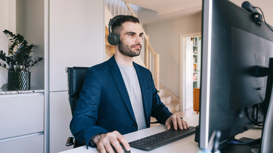 Headset Logitech Zone Wireless 2 ES sivý Muž pracujúci pri počítači s headsetom Logitech Zone Wireless 2 ES v domácej kancelárii