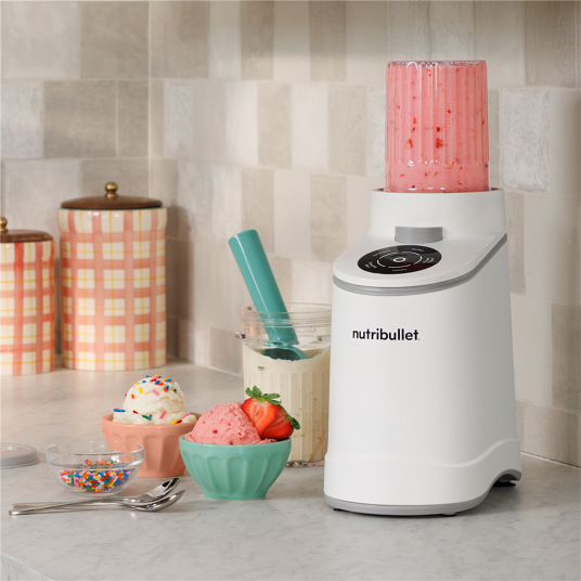 Zmrzlinovač Nutribullet Chill NBD0503W biely Nutribullet zmrzlinovač na kuchynskej linke s pripravenou zmrzlinou a smoothie v miskách.