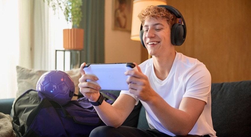 Hráč hrá mobilnú hru na pohovke s nasadeným herným headsetom Logitech G325 LIGHTSPEED Wireless