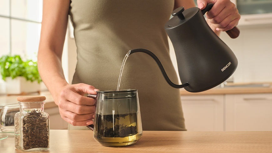 Rýchlovarná kanvica Sencor SWK 2828BK, 0,6 l čierna Žena zalieva sypaný čaj v sitku kanvice.