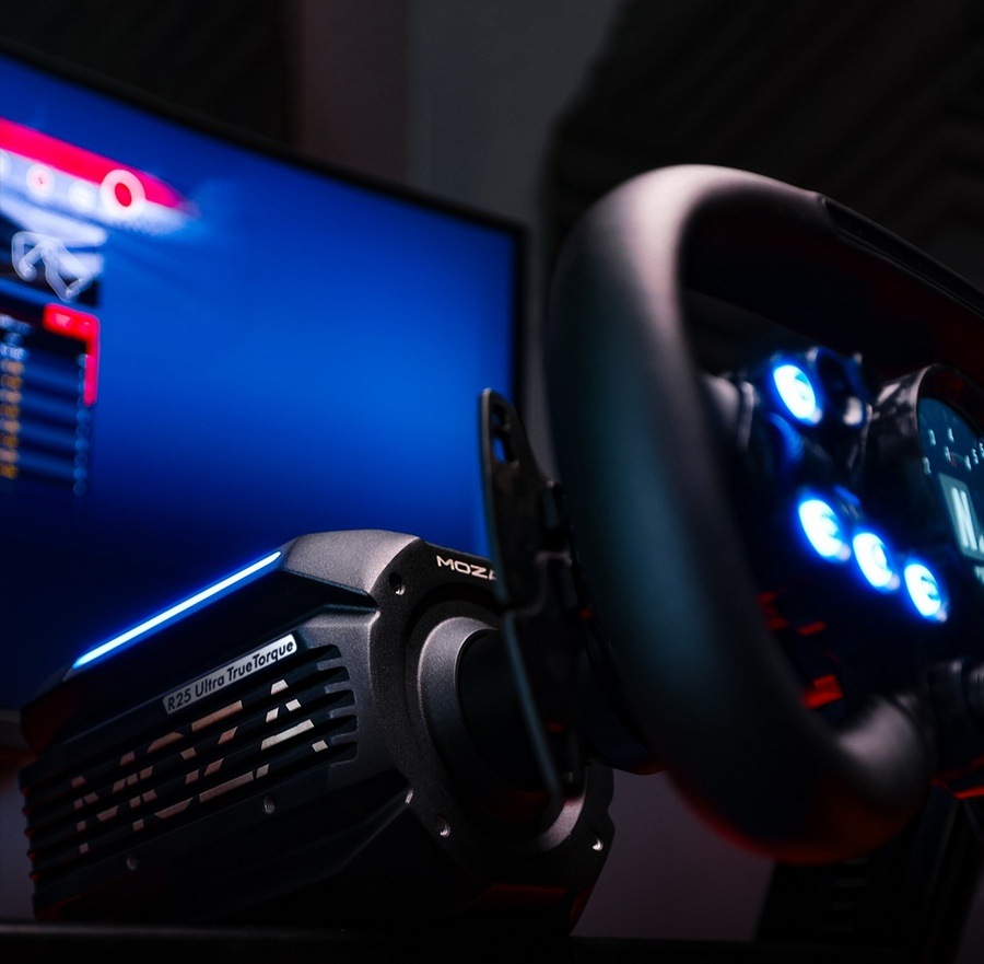 Základňa Moza Racing R25 Ultra Direct Drive hliník Detailný záber na závodné príslušenstvo s volantom so svietiacimi modro tlačidlami a displejom zobrazujúcim herné nastavenie v tlmene osvetlenej miestnosti.