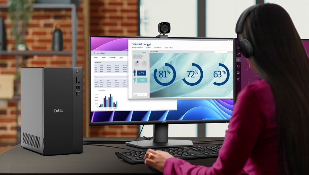 Stolný počítač Dell Pro Tower Essential QVT1260 čierny Užívateľka s nasadenými slúchadlami sedí pri stole a pracuje na počítači. Na monitore počítača sú zobrazené finančné grafy a tabuľky, nad obrazovkou je umiestnená webová kamera. Na stole je vidieť stolný počítač s nápisom „Dell“.