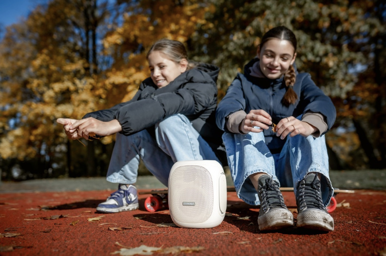Dve dievčatá počúvajú prenosný reproduktor Concept SoundJoy BR5036 počas vonkajšieho posedenia
